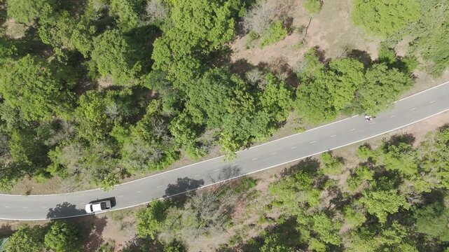 Aerial drone footage of a pickup truck driving on a rural road through countryside landscape. Scenic view of travel, transportation, and freedom in nature