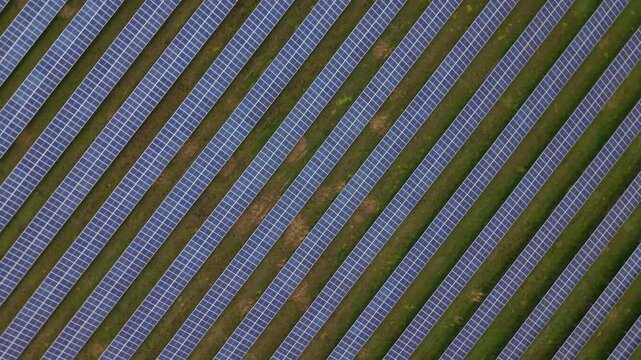 Aerial view of rows of solar panels creating a geometric pattern with contrasting blue and green, capturing a modern energy landscape, Burwell, England, United Kingdom.