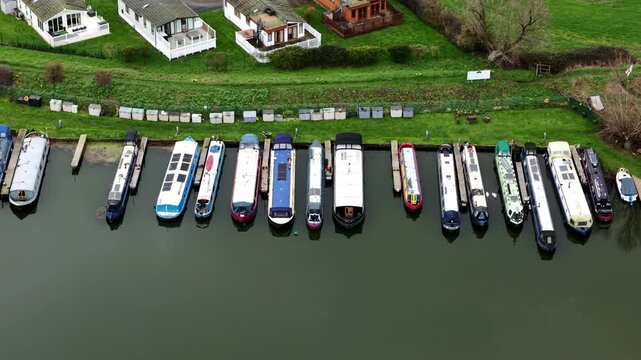 Aerial view of boats docked at Stretham Ferry Marina, a picturesque scene with colorful boats contrasting against the dark water, Ely, United Kingdom.