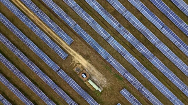 Aerial view of a vast solar farm, the panels reflecting the sky, creating a textured blue and brown landscape, Former RAF Alconbury, Huntingdon, United Kingdom.