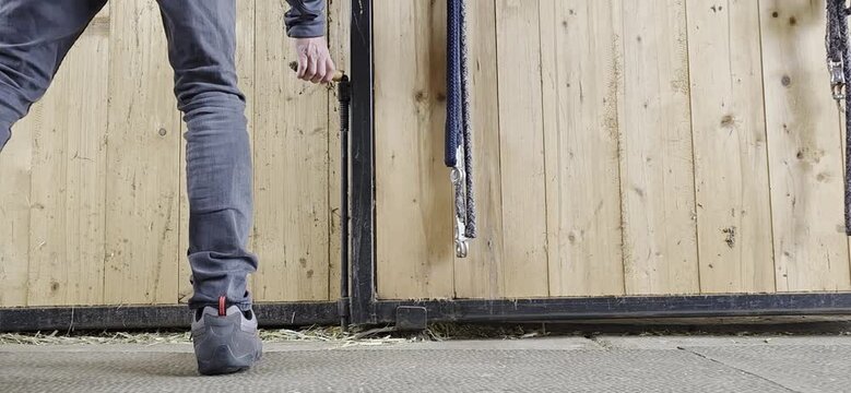 a young man opens and closes the stable door