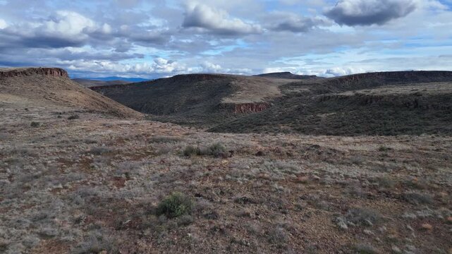 Aerial view of stark canyons, hills, and scrub brush under a cloudy sky, showing contrasting textures and tones, French Gulch, Arizona, United States.