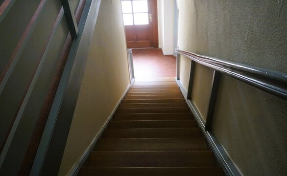 Innenausstattung von altem Treppenhaus in Haus mit brauner Holztreppe, Holzgel&auml;nder und Haust&uuml;r mit Licht 