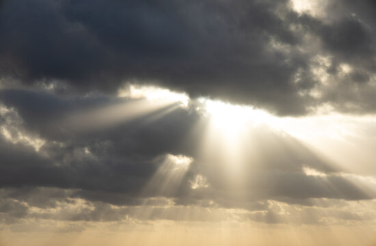 Dramatic sun rays breaking through dark storm clouds over Caribbean sea near Cozumel Mexico creating crepuscular rays over the ocean