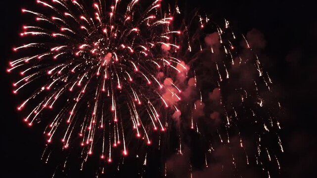 A spectacular display of red fireworks exploding in the night sky, creating a dazzling visual effect.