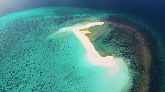 Aerial drone view of a curved sandbar in Coron Bay, Palawan, Philippines, surrounded by calm turquoise waters with dramatic mountain silhouettes in the background