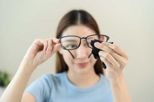Close-up person cleaning eyeglasses with microfiber fabric.