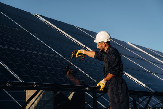 Crystal clear surface, installation, using tool. Male solar engineer examining photovoltaic panels at a power station