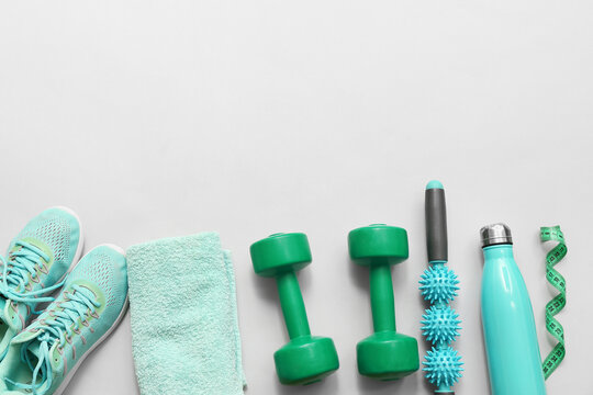 Sneakers, measuring tape and different sports equipment on grey background