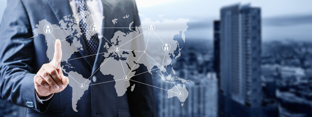 A businessman in a suit interacts with a digital world map overlay, illustrating global...