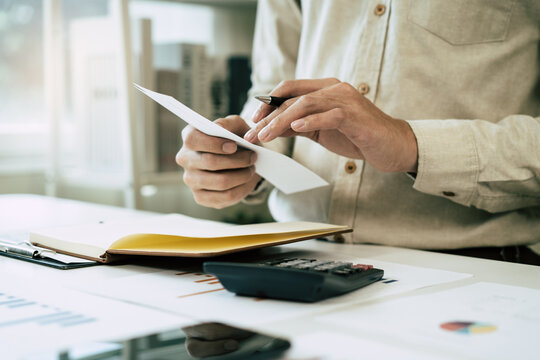 Deduction planning, debt asian accountant hand using calculator to calculating money balance from bill and income, cost budget expenses for pay money form personal individual on table at home.