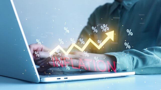 Chart shows rising trend in inflation with a person's hands typing on a laptop in a bright office setting.