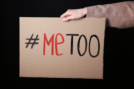 Woman holding cardboard paper with hashtag METOO on dark background