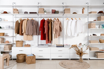 Big wardrobe with different stylish clothes and accessories in dressing room