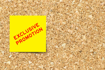 Yellow note paper with word exclusive promotion on cork board background with copy space