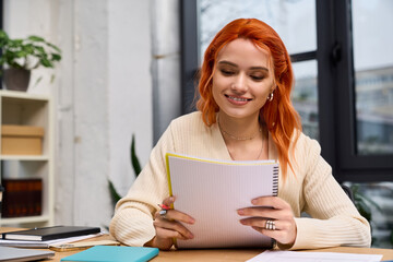 Obraz premium Young woman with red hair engages in creative tasks in a modern office space