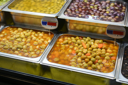 
Various olives on a counter displayed for sale at the market.