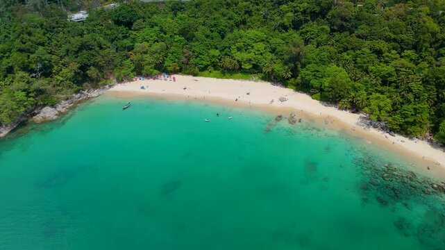 Capturing Haad Laem Sing Beach in Phuket Thailand from an aerial viewpoint. People relax on the sandy shore and swim in clear turquoise waters