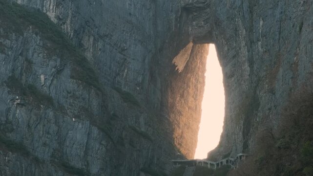 Natural stone arch with long staircase between towering cliffs at sunrise.in Tianmen Mountain National Forest Park, Zhangjiajie, Hunan, China. Tianmenshan cave with 999 steps