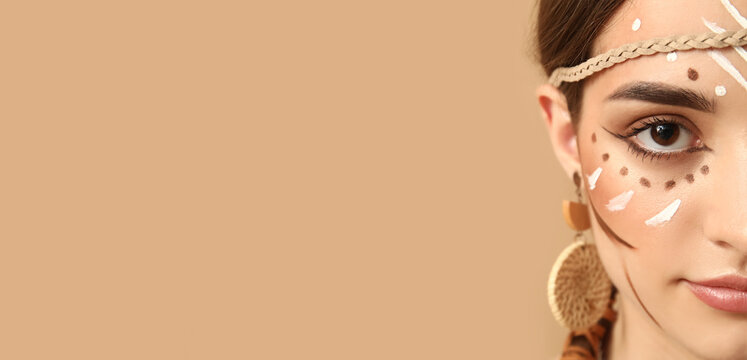 Beautiful young woman with Indian makeup on beige background, closeup. Native American Heritage Month