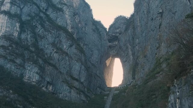 Heaven gate stone arch glowing at sunrise with steep staircase between towering cliffs at sunrise.in Tianmen Mountain National Park, Zhangjiajie, Hunan, China. Tianmen cave with 999 steps