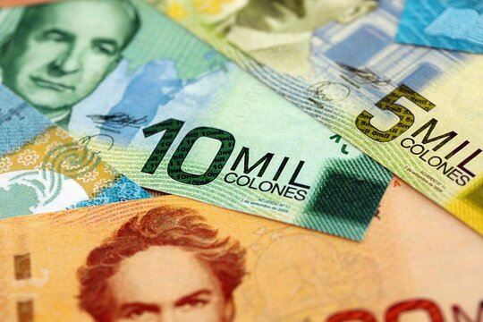 Costa Rican old and new colon money bills pile on table. Costa Rica banknotes of CRC currency close up. Concept of business, economy and banking in Costa Rica