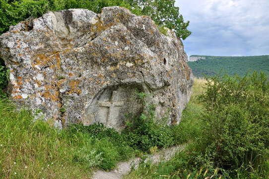 ncient rock with a carved cross among wild nature and mountains, historical site and natural landmark with peaceful spiritual atmosphere