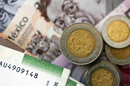 Mexican peso money bills and centavo coins pile on table. Mexico coins on banknotes of MXN currency close up. Concept of business, taxes and banking in Mexico