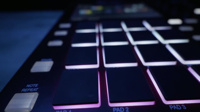 A slider shot moves across the glowing pads of a professional red drum machine in a dark studio. Concept of music production, electronic beats, and creative audio technology.