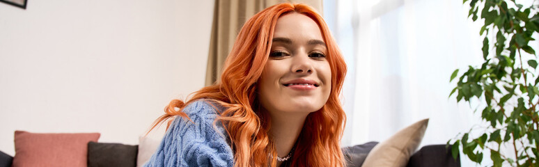 Naklejka premium Young woman enjoys cozy winter vibes in her modern apartment with red hair