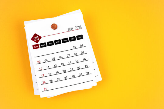 May 2026 calendar page with wooden push pin on yellow, position with copy space.