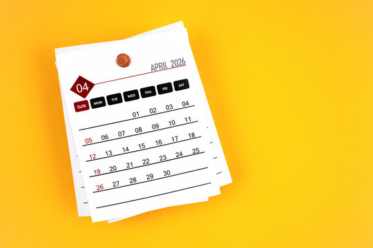 April 2026 calendar page with wooden push pin on yellow, position with copy space.