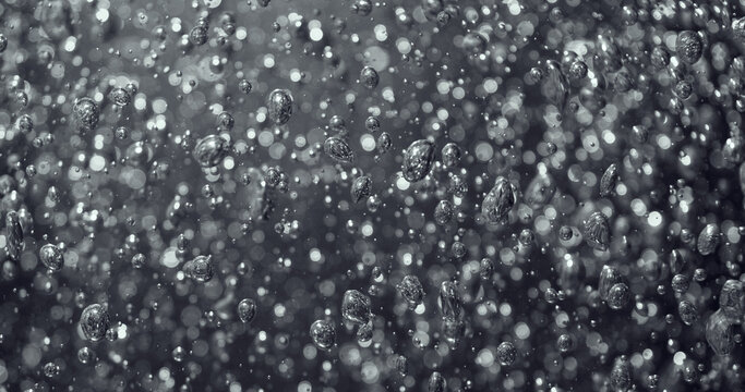 Abstract macro background of rising bubbles in liquid. Sparkling droplets and soft bokeh create a dynamic texture resembling carbonation in sparkling water, soda or champagne.