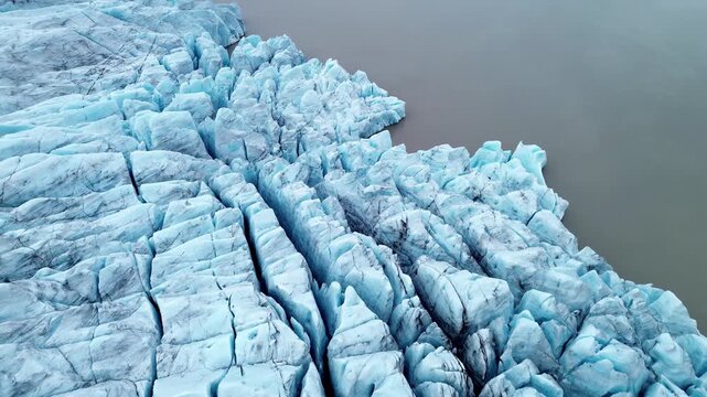 Aerial drone view of Breioamerkurjokull glacier ice formations near Jokulsarlon Lagoon, Iceland. Sharp blue ice blocks and deep cracks form abstract frozen patterns in the glacial landscape