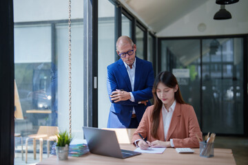 Fototapeta premium Manager supervising female employee writing notes in modern office