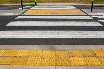 low angle view of a pedestrian crossing withtactile paving tiles. raised truncated domes with a detectable warning surface for visually impaired pedestrians. transportation background © mailcaroline
