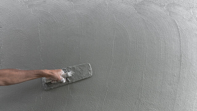 Hand plasterer plastering cement wall background, hand worker brush rough concrete floor for smooth manual well free space for text with occupations about building construction site
