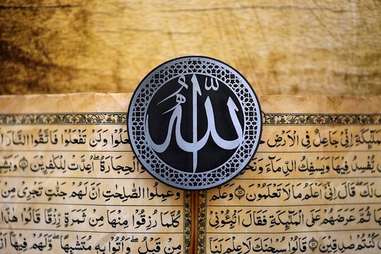 Sign with Islam inscription on Muslim holy book in mosque. Details of arabic calligraphy on sticker. Concept of Islam religion and praying in arabic countries