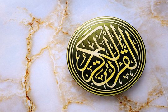 Sign with Al Quran inscription on table in mosque. Details of arabic calligraphy on paper sticker. Concept of Islam religion and praying in arabic countries