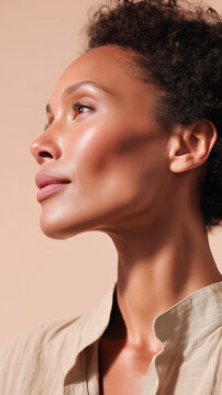 Mixed race woman with radiant glowing skin poses in side profile against soft beige background. Her luminous complexion and natural beauty perfectly capture skincare hydration and wellness themes.
