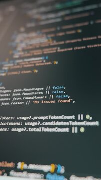 Programming code lines scroll on a dark vertical monitor with AI integration. Concept of vibe coding, modern software development, and automated application building.