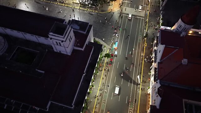 Aerial Night View of Urban Street Traffic With Pedestrians and Lit City Buildings