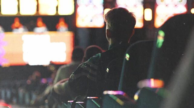 Young man playing slot machine in casino gaming room
