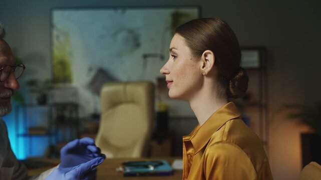 Male ENT doctor in gloves palpating woman's neck, checking for infection