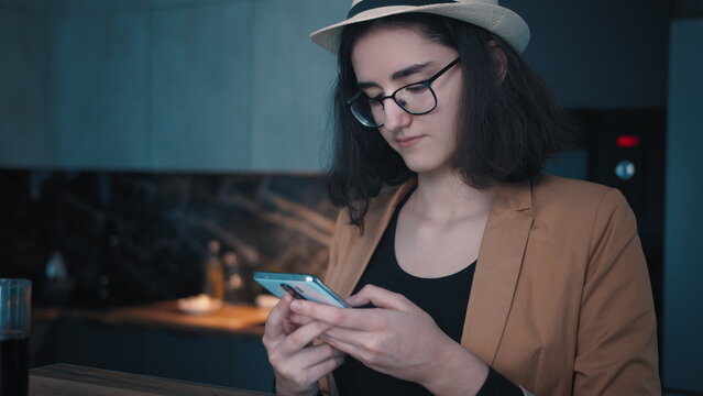 teen girl in the kitchen texting on the phone, chating with friends, relationship, read some information, have fun and enjoy