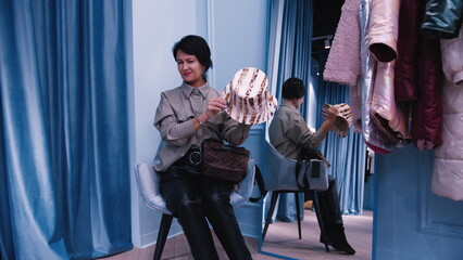 Naklejka premium woman designer measures hat in clothing store, have fun and enjoy