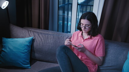 Obraz premium Young Woman Using Smartphone on Couch at Home, have fun and enjoy
