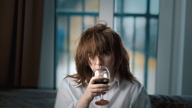 close up of a sad woman with glass of wine at home looking at camera, depression, have fun and enjoy