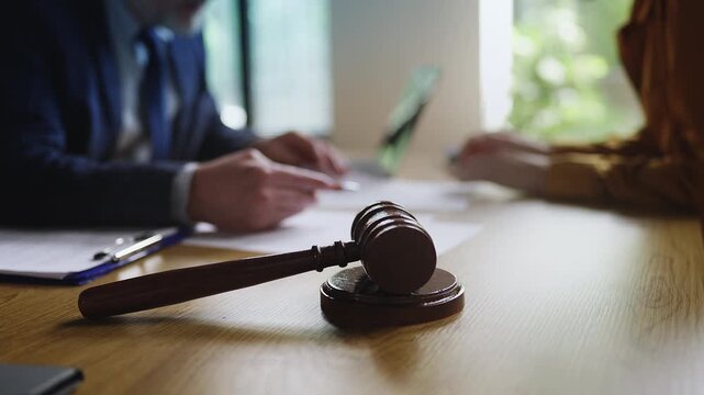 Gavel on the desk during a legal meeting between male lawyer and female client