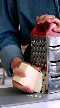 Woman Grating Cheese With A Metal Grater In The Kitchen, Vertical Video
